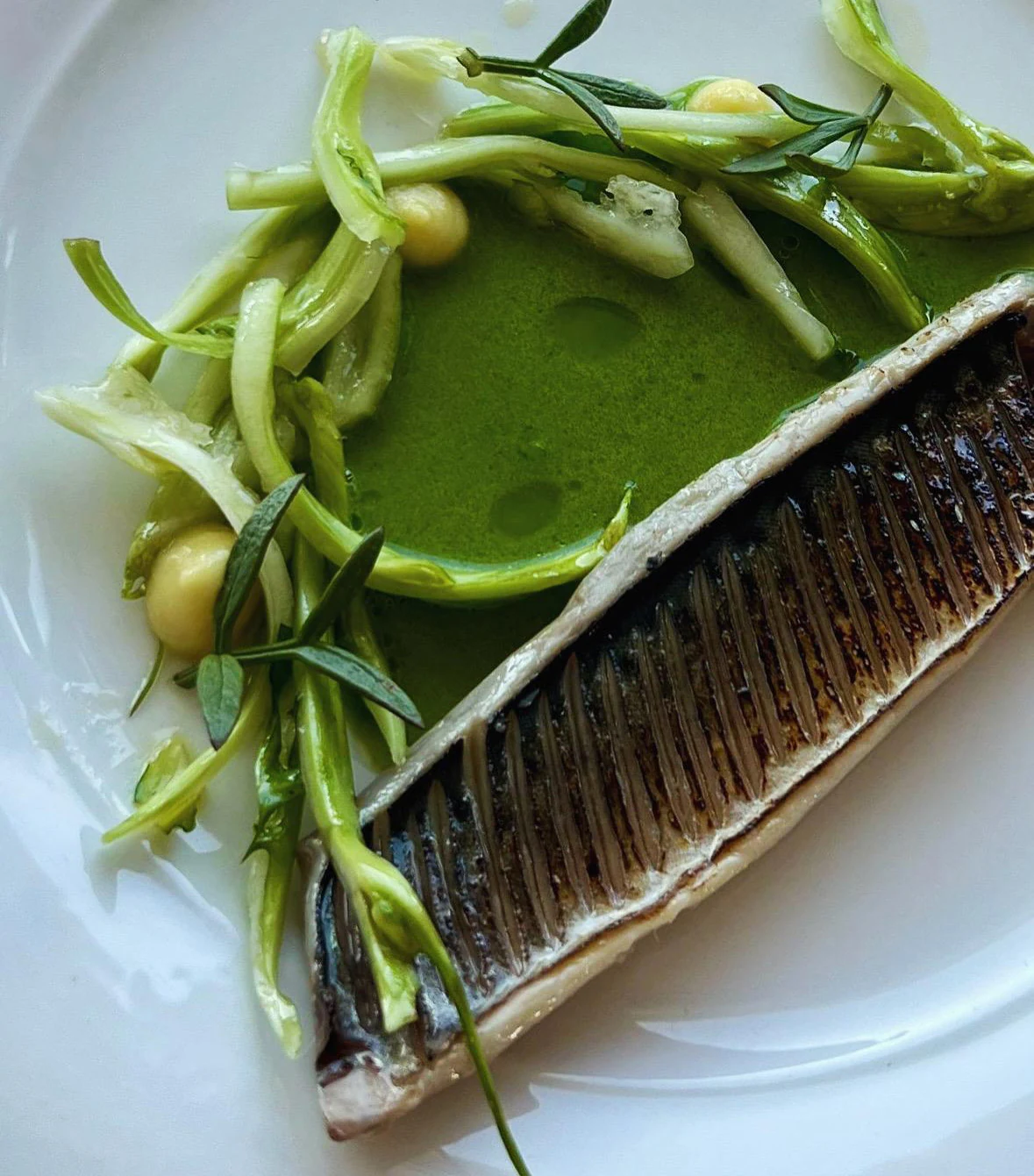 Immagine originale: dettaglio di un piatto di pesce con vegetali e salsa verde.