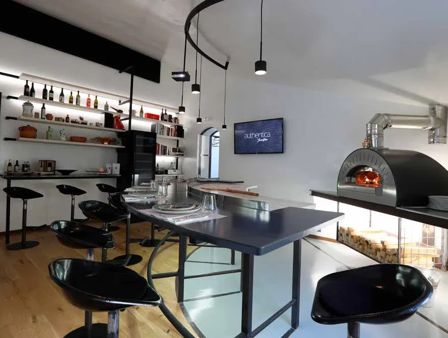 Interno di Authentica con tavolo, forno e scaffali.