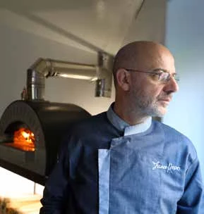 Persona in abito da chef accanto al forno.