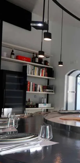 Tavolo con calici, illuminazione e scaffali.
