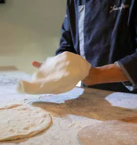Gesto di lavorazione dell’impasto sul piano di lavoro.