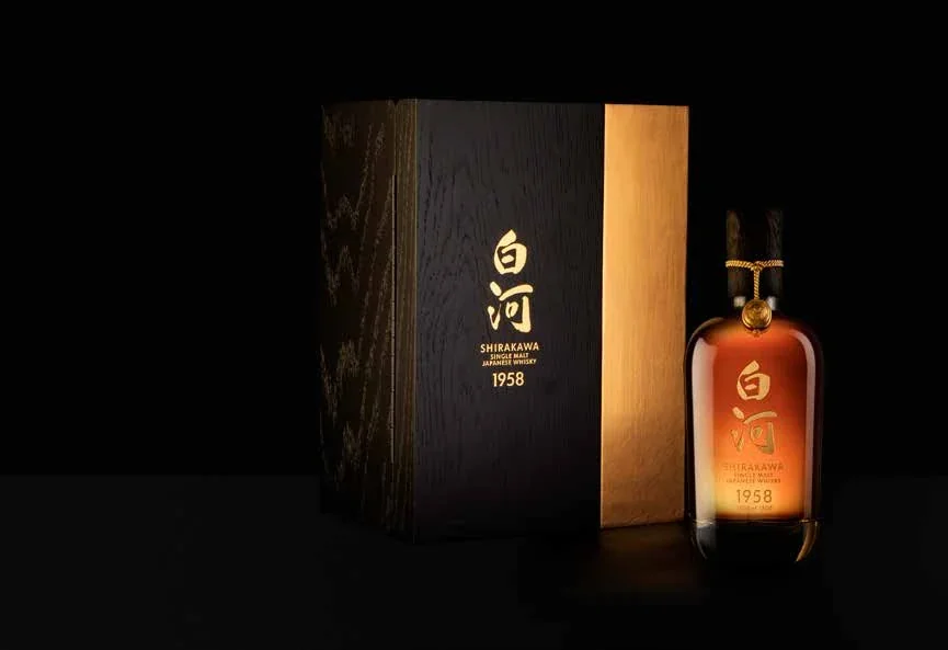 Bottiglia e confezione di whisky Shirakawa 1958 su sfondo nero.