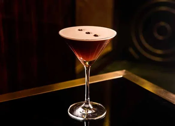 Cocktail in coppa in un ambiente con luci calde.