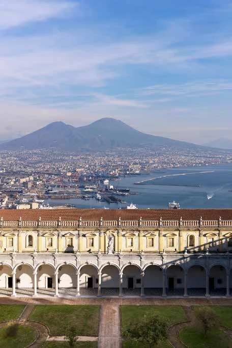 Veduta di Napoli con il Vesuvio e architettura monumentale.