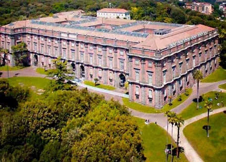 Veduta dall’alto di un edificio monumentale tra prati e alberi.