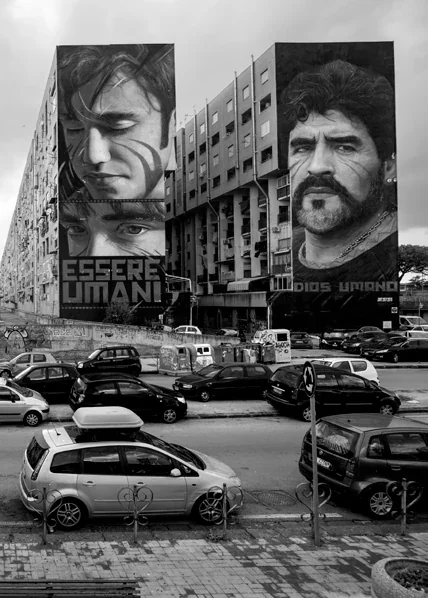 Scena urbana in bianco e nero con grandi ritratti e scritte Esseri umani.