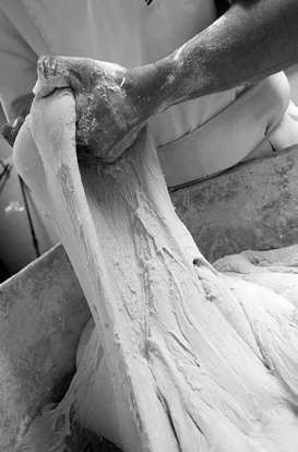 Mani che lavorano l’impasto, in bianco e nero.